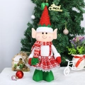 Dettaglio della bambola elfo di Natale con cappello e sciarpa su un tavolo festivo - Stile Piede Verde