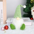 Nain de Noël avec bonnet rayé vert sur tapis en fourrure blanche près du sapin - Vert