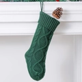 Bosgroene gebreide kerstsok met kabelpatroon hangend aan een witte minimalistische haard - Groen