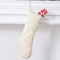 Detail van een crèmekleurige gebreide kerstsok met bessen hangend aan een witte haard - Melkwit