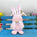 Dettaglio dello gnomo coniglio di Pasqua rosa a quadri con cuore su una panca in legno blu - Stile Gnomo Rosa / Coniglio Rosa