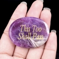 Purple amethyst worry stone with golden This Too Shall Pass engraving held in hand - Amethyst