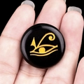 Pierre d'obsidienne noire polie ronde avec gravure dorée de l'Œil de Horus - Obsidienne