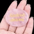 Pierre de quartz rose tenue en main avec gravure dorée Relax the body calm the mind - Quartz rose
