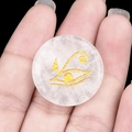 Disque en cristal blanc poli avec l'œil d'Horus doré tenu dans la paume d'une main - Cristal blanc