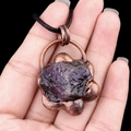 Vintage copper-wrapped purple raw crystal flower pendant necklace held in hand - Amethyst