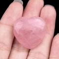 Handheld heart-shaped rose quartz stone pendant with natural texture and soft pink color - Rose Quartz