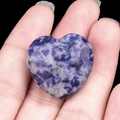 Hand holding a heart-shaped blue and white sodalite stone with natural marble texture - Sodalite