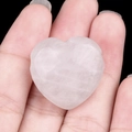 Natural heart-shaped rose quartz pendant held in hand with clear stone texture - White Crystal