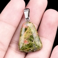 Polished unakite stone trapezoid pendant with silver metal clasp held in hand - Unakite
