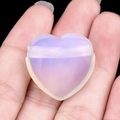 Hand holding a 25mm purple opalescent heart stone pendant with polished finish - Opal (Synthetic)