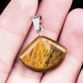 Tiger eye stone fan-shaped pendant with silver clasp held in hand for size visualization - 20mm Tiger Eye
