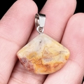 Natural agate fan pendant with orange silk texture and silver metal clasp held in hand - 20mm Crazy Agate