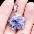 Pendentif étoile en sodalite bleue avec bélière argentée présenté sur la paume - Jaspe à Points Bleus / 20mm