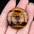 Pendentif donut en pierre œil de tigre marron avec effet chatoyant sur un fond noir uni - Œil de tigre