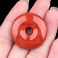 Pendentif donut en jaspe rouge avec veines naturelles tenu à la main pour la taille - Jaspe Rouge
