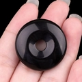 Pendentif donut en obsidienne noire polie tenu en main pour accessoires bijoux DIY - Obsidienne