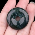 Pendentif donut en pierre aventurine verte polie présenté en main pour la taille - Agate de l'Inde