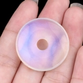 Pendentif donut en cristal marbré violet et bleu translucide tenu à la main - Opalite Artificielle