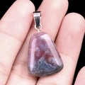 Natural crystal trapezoid pendant with silver bail held against a black background - India Agate
