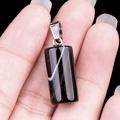 Black and white striped agate cylinder pendant held in palm for scale comparison - Black Agate