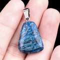 Natural blue trapezoid crystal pendant with silver metal clasp held in hand - Blue Lace Stone
