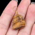 Handmade tiger eye stone wire wrapped pendant with golden wire held in hand - Tiger's Eye