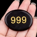 Polished black crystal palm stone featuring golden 999 engraving held in hand - Obsidian