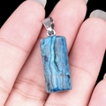 Natural blue turquoise cylinder crystal pendant with silver clasp held by hand - Blue Lace Stone