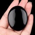 Pierre de paume ovale en cristal noir poli tenue à la main pour massage et SPA - Obsidienne