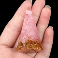 Roze kwarts en goudfolie piramide hars decoratie in de hand op zwarte achtergrond - Rozenkwarts