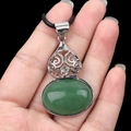 Vintage green oval stone pendant with ornate silver metal setting and black woven cord - Green Aventurine