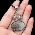 Oval black shell pendant with silver hollow patterns and a clear crystal on a cord - Black Shell