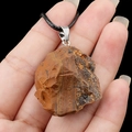 Natural tiger eye raw stone pendant with rustic texture on black woven cord - Tiger's Eye