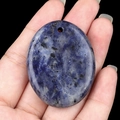 Polished oval blue sodalite palm stone pendant held in hand for scale reference - Blue Sodalite