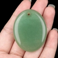Handheld view of a polished oval green aventurine stone pendant with top drill hole - Green Aventurine