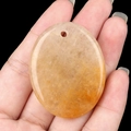 Handheld light orange oval palm stone pendant with natural mineral textures and hole - Yellow Jade