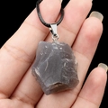 Collier avec pendentif en cristal gris naturel et cordon noir tenu dans la main - Agate Grise