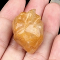 Hand carved yellow crystal heart shaped stone with natural texture and golden hues - Yellow Jade