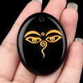 Oval black obsidian pendant featuring golden Buddha eyes of wisdom with top drill hole - Obsidian