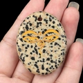 Handheld Dalmatian Jasper stone pendant featuring an etched golden Buddha wisdom eye - Dalmatian Jasper
