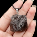 Pendentif en quartz fumé naturel avec cordon noir tenu dans la main d'un modèle - Quartz fumé