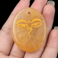 Oval natural yellow crystal palm stone pendant with golden Wisdom Eyes engraving - Yellow Jade