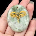 Engraved light green palm stone pendant featuring golden Wisdom Eyes design - Xiu Jade