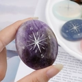 Polished oval amethyst palm stone featuring a silver compass engraving for healing - Amethyst