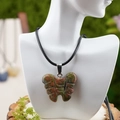 Engraved unakite stone butterfly pendant necklace with black braided cord on model - Unakite Style