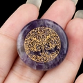 25mm round amethyst crystal disc with golden tree of life engraving held in hand - Amethyst