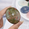 Green unakite palm stone with engraved star compass design for meditation and healing - Unakite