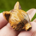 Handcrafted tiger eye stone fox head carving featuring natural brown stripes in hand - Tiger's Eye