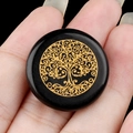 25mm black obsidian stone with gold tree of life engraving held in a hand - Obsidian